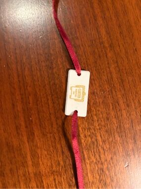 Red Ribbon bracelet with Gold Cartier Logo . Fragrance ceramic bracelet.